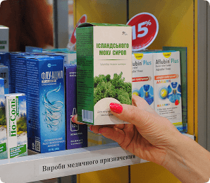 Рука бере ліки з полиці в аптеці