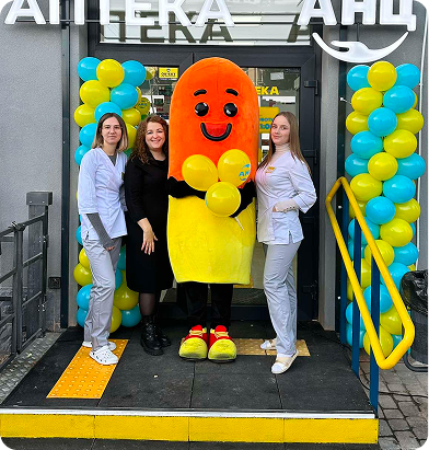 ANC pharmacy team with mascot at store entrance